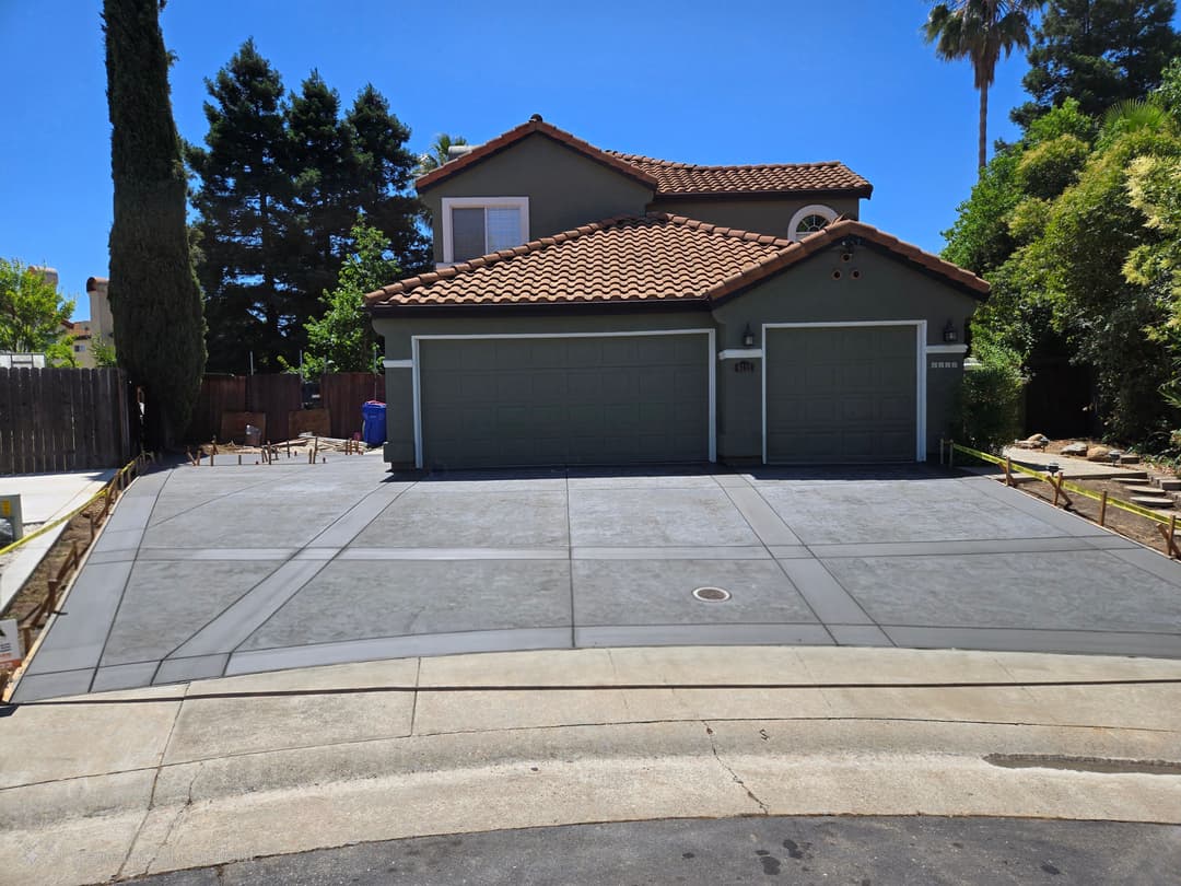 Modern two-story house with a tiled roof, double garage, and newly paved driveway.